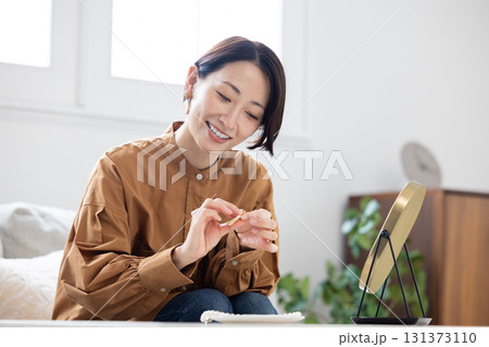 リビングで鏡を見ながらイヤリングをつける女性 131373110