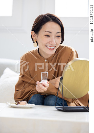 自宅のリビングで化粧水をつけるスキンケア中の女性 131373115