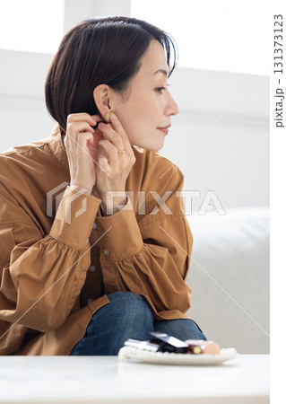 リビングでイヤリングをつける女性 リビングでイヤリングをつける女性 131373123