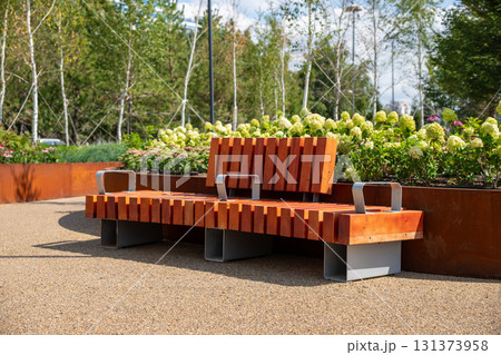 modern wooden bench in landscaped park area with green grass and seasonal flowers. comfortable urban environment. improvement, beautification, renovation, improving quality of life 131373958