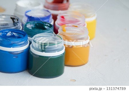 colorful acrylic paint in jar, grey dirty background,  artists materials photography 131374789