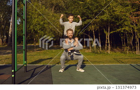 Child boy sitting on fathers shoulders doing sport fit exercises together on gymnastic bar. Child boy sitting on fathers shoulders doing sport fit exercises together on gymnastic bar. 131374973