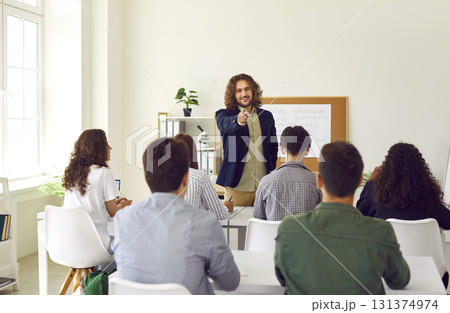 Male friendly teacher at the lesson in high school. Young students working in classroom Male friendly teacher at the lesson in high school. Young students working in classroom 131374974