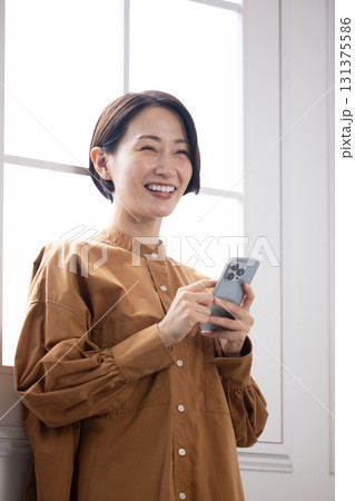 スマートフォンを見ながら微笑むミドル女性 131375586