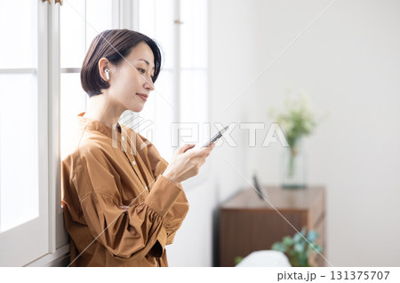 スマホとワイヤレスイヤフォンで音楽を楽しむミドル女性 スマホとワイヤレスイヤフォンで音楽を楽しむミドル女性 131375707