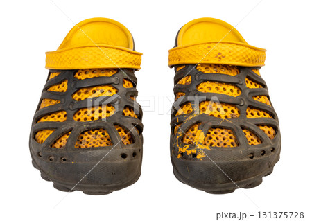 dirty worn yellow and black garden rubber sandals or shoes with perforated design isolated on white background. Front view 131375728