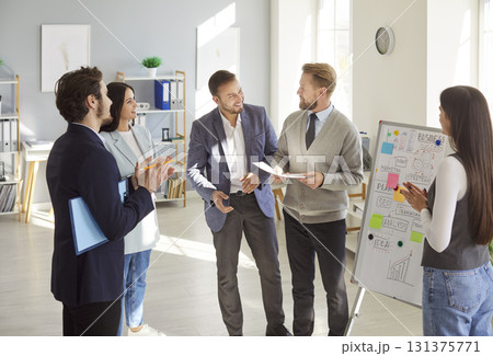 Cheerful business professionals discussing ideas and analyzing plans during team meeting in office. 131375771