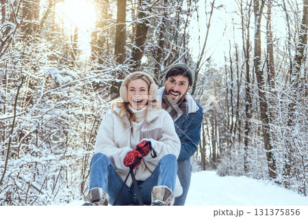 Young happy coupe sitting on a sled and feeling excited Young happy coupe sitting on a sled and feeling excited 131375856