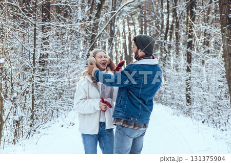 Happy couple spending time in the winter forest and looking enjoyed and excited Happy couple spending time in the winter forest and looking enjoyed and excited 131375904