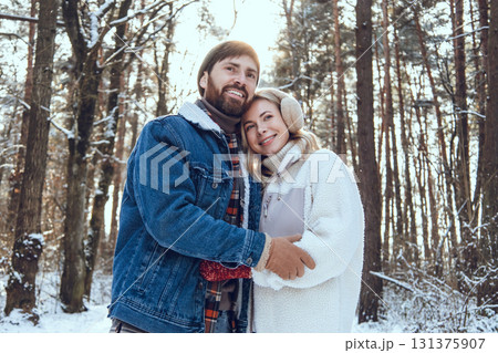 Happy couple spending time in the winter forest and looking enjoyed and excited Happy couple spending time in the winter forest and looking enjoyed and excited 131375907
