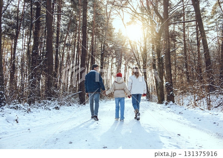 Family having a walk in a winter forest while holding hands Family having a walk in a winter forest while holding hands 131375916