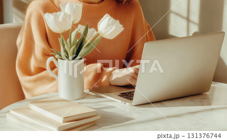 Woman freelance working on laptop with coffee and tulips, minimalist style, warm tones 131376744