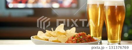 Super Bowl game party, glass of beer and plate of chips with salsa next to television screen Super Bowl game party, glass of beer and plate of chips with salsa next to television screen 131376769
