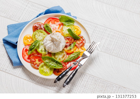 Fresh burrata served on slices of colorful tomatoes Fresh burrata served on slices of colorful tomatoes 131377253