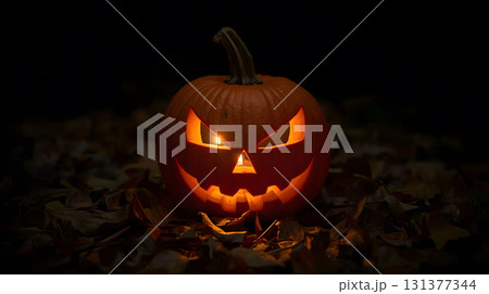 Halloween pumpkin carved with a sinister face illuminated by candlelight at night 131377344