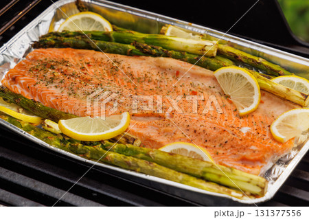 Grilled salmon fillets and asparagus sizzling on a barbecue grill 131377556
