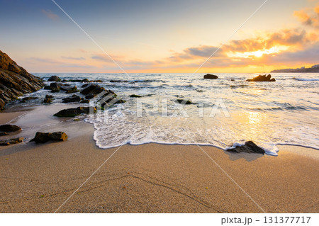 sunrise on the beach. beautiful summer landscape for vacation at the sea. rocks on the sand. calm waves on the water. sun behind clouds on the sky. wide panoramic view of bamboo beach in sozopol 131377717