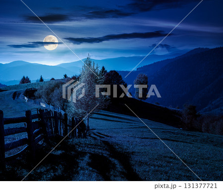 mountainous rural landscape in autumn at night. field behind the wooden fence in full moon light. scenery in fall season. forest on the hill. ridge in the distance mountainous rural landscape in autumn at night. field behind the wooden fence in full moon light. scenery in fall season. forest on the hill. ridge in the distance 131377721