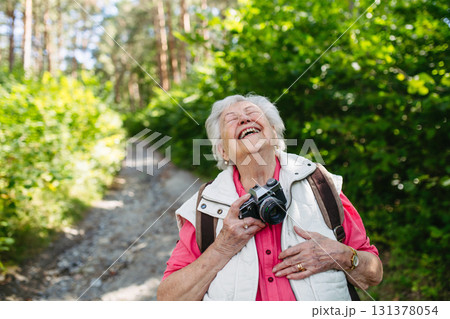 Elderly woman photographing nature during forest walk. Elderly woman photographing nature during forest walk. 131378054