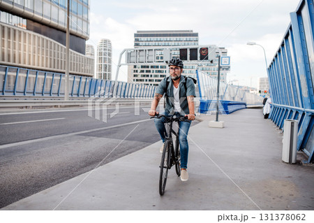 City commuter riding bike on street, wearing backpack. 131378062