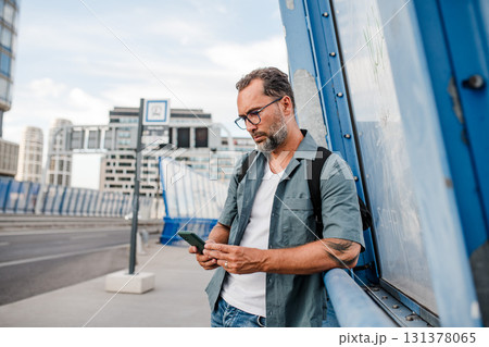 Mature man walking home from work, texting on smartphone. Mature man walking home from work, texting on smartphone. 131378065