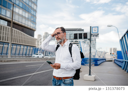 Mature businessman walking home from work, texting on smartphone. Mature businessman walking home from work, texting on smartphone. 131378073