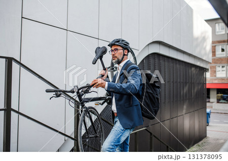 City commuter carrying bicycle up urban stairs. City commuter carrying bicycle up urban stairs. 131378095