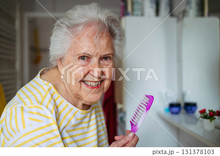Senior woman combing her hair in bathroom. Senior woman combing her hair in bathroom. 131378103