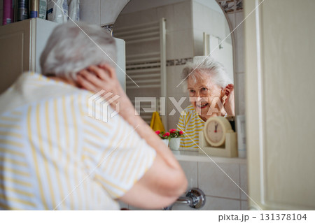 Older woman checking skin and appearance in bathroom. Older woman checking skin and appearance in bathroom. 131378104