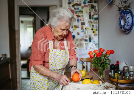 Senior lady in apron preparing fresh fruit at home. Senior lady in apron preparing fresh fruit at home. 131378106