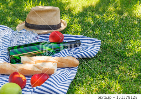 Picnic with wine, fruits, and baguette on a green meadow Picnic with wine, fruits, and baguette on a green meadow 131378128