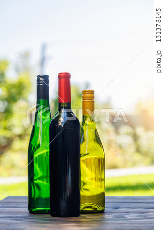 Wine bottles on a wooden table, glowing with sunny bokeh in the background Wine bottles on a wooden table, glowing with sunny bokeh in the background 131378145