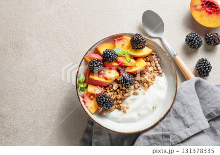 Natural Greek yogurt with granola or muesli, peach and blackberry in a bowl on a light background Natural Greek yogurt with granola or muesli, peach and blackberry in a bowl on a light background 131378335
