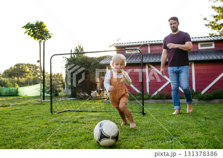 Little boy playing football with father in backyard. Little boy playing football with father in backyard. 131378386