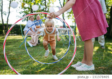 Family enjoying outdoor summer gathering with playful activities. 131378405