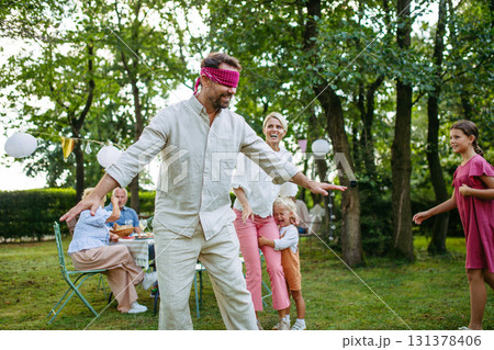 Family enjoying outdoor summer gathering with playful activities. Family enjoying outdoor summer gathering with playful activities. 131378406