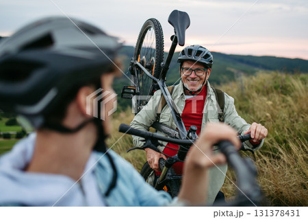 Older couple cycling together in nature, smiling and enjoying outdoor adventure. Older couple cycling together in nature, smiling and enjoying outdoor adventure. 131378431