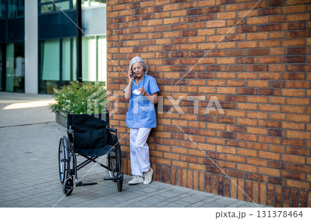 Nurse in uniform pushing empty wheelchair. 131378464