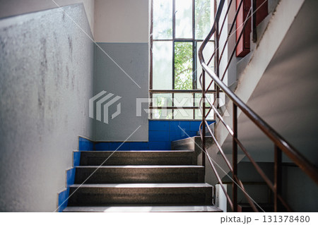 Old apartment building staircase with window light. 131378480
