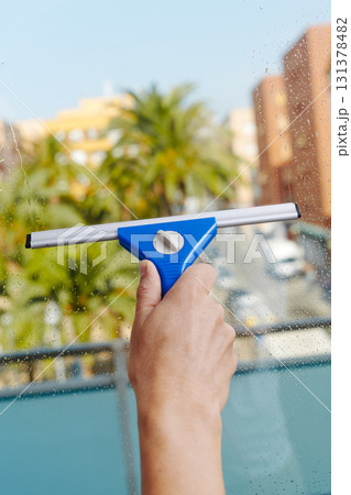 a man dries a balcony glass door a man dries a balcony glass door 131378482