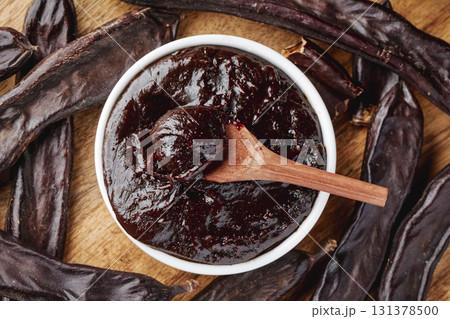 carob cream in a bowl and pods on a wooden table carob cream in a bowl and pods on a wooden table 131378500