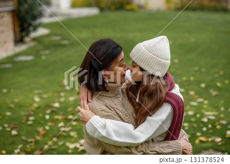 Young granddaughter with gradmother hugging, standing in garden. Young granddaughter with gradmother hugging, standing in garden. 131378524