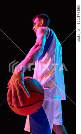 Basketball player holding ball in neon light with determination and strength Basketball player holding ball in neon light with determination and strength 131378660
