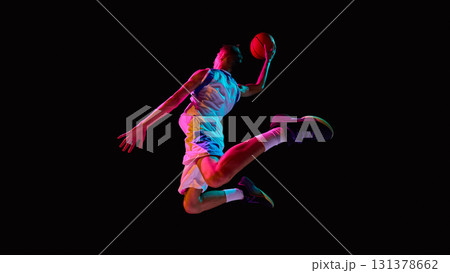 Basketball player soaring with ball in neon lights showing athletic power Basketball player soaring with ball in neon lights showing athletic power 131378662