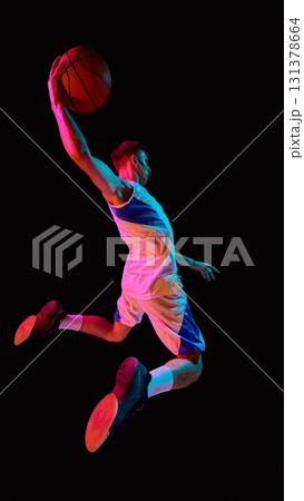 Basketball player dunking in neon lights with fierce emotional power 131378664