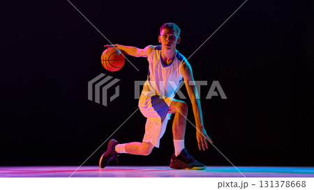 Basketball player dribbling low in neon lights with powerful focus Basketball player dribbling low in neon lights with powerful focus 131378668