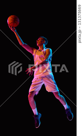 Basketball player reaching for layup in neon lights with determination Basketball player reaching for layup in neon lights with determination 131378669