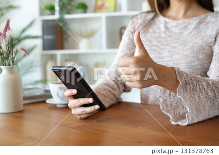 Woman hands gesturing thumb up and holding phone 131378763