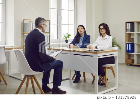 Two business women in office who are engaged in recruiting employees interviewing man in office. 131378928