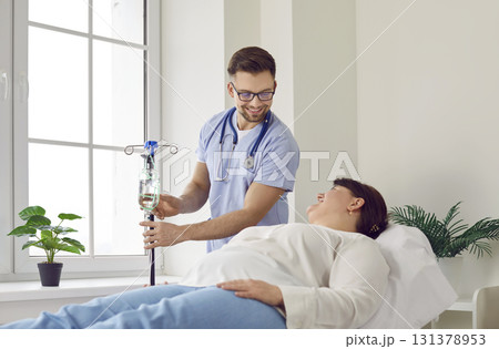 Nurse gives an IV line to a woman patient lying on the medical bed at the hospital Nurse gives an IV line to a woman patient lying on the medical bed at the hospital 131378953